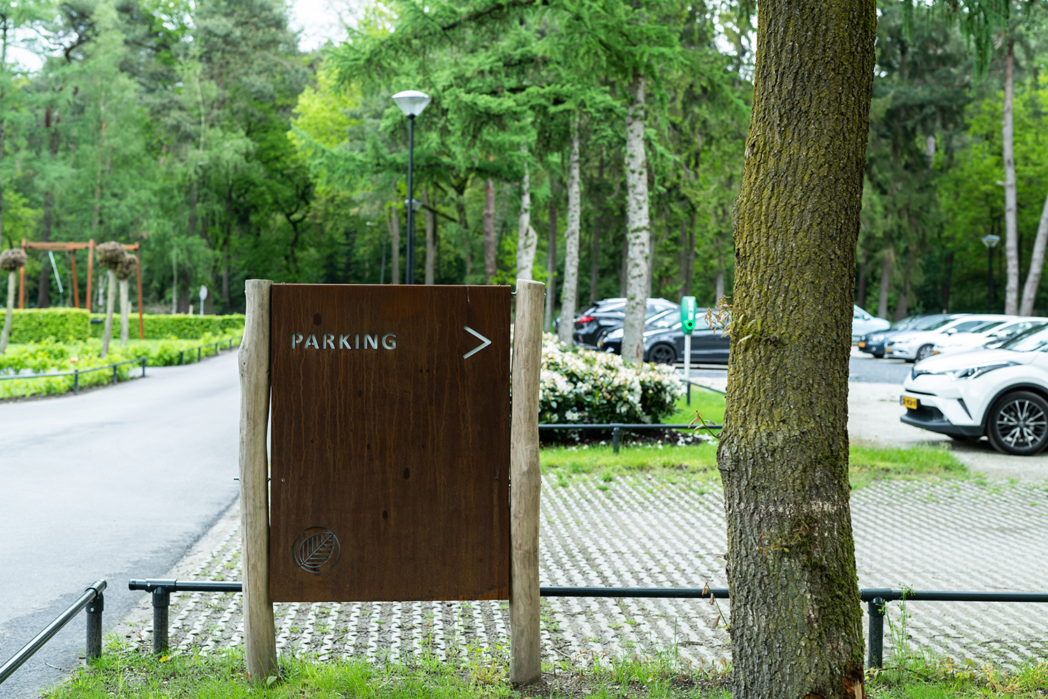 Parkeerplaats van De Werelt Lunteren met bewegwijzering op de voorgrond