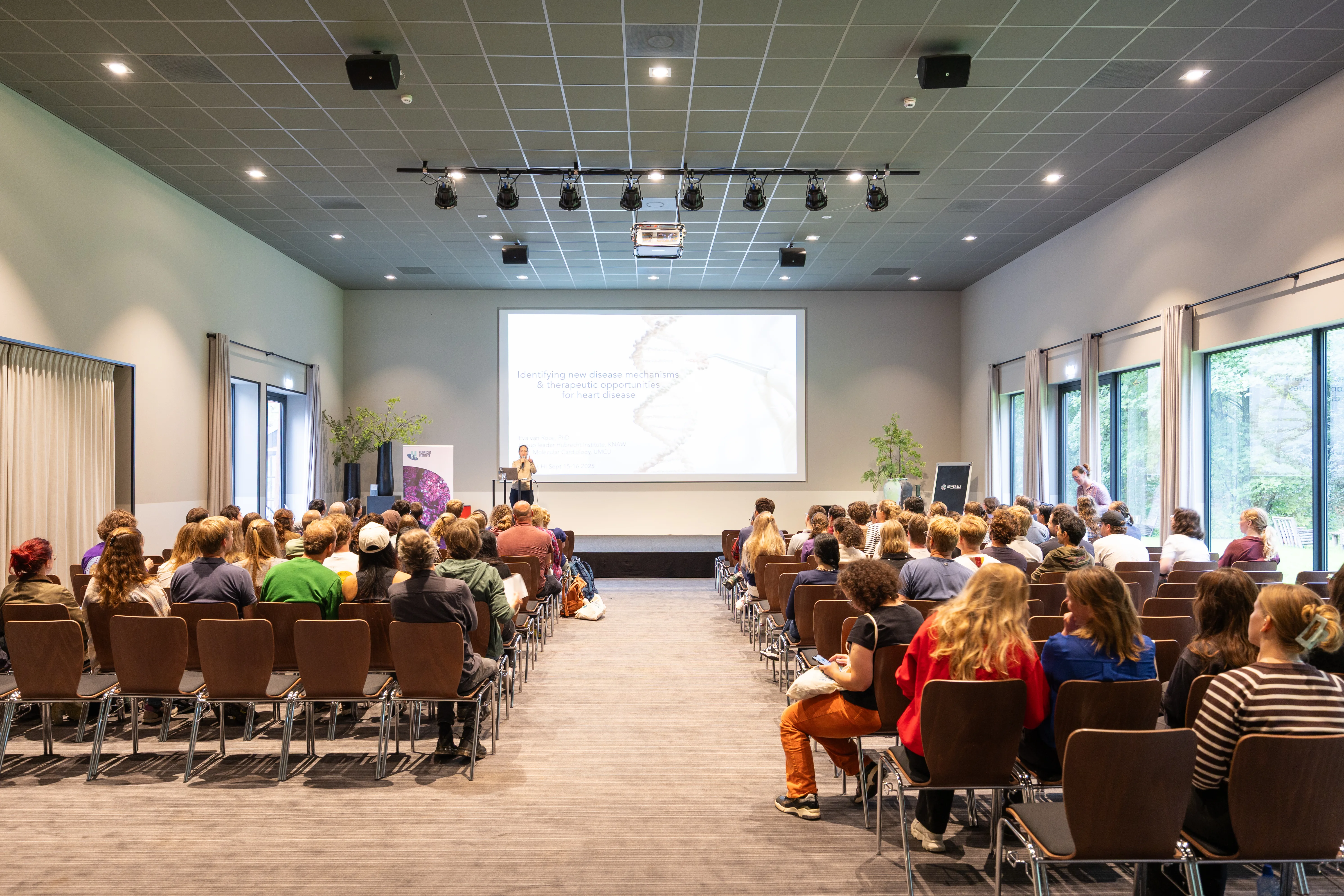 Deelnemers van een evenement zitten in zaal Air bij de Werelt Lunteren te kijken naar een presentatie