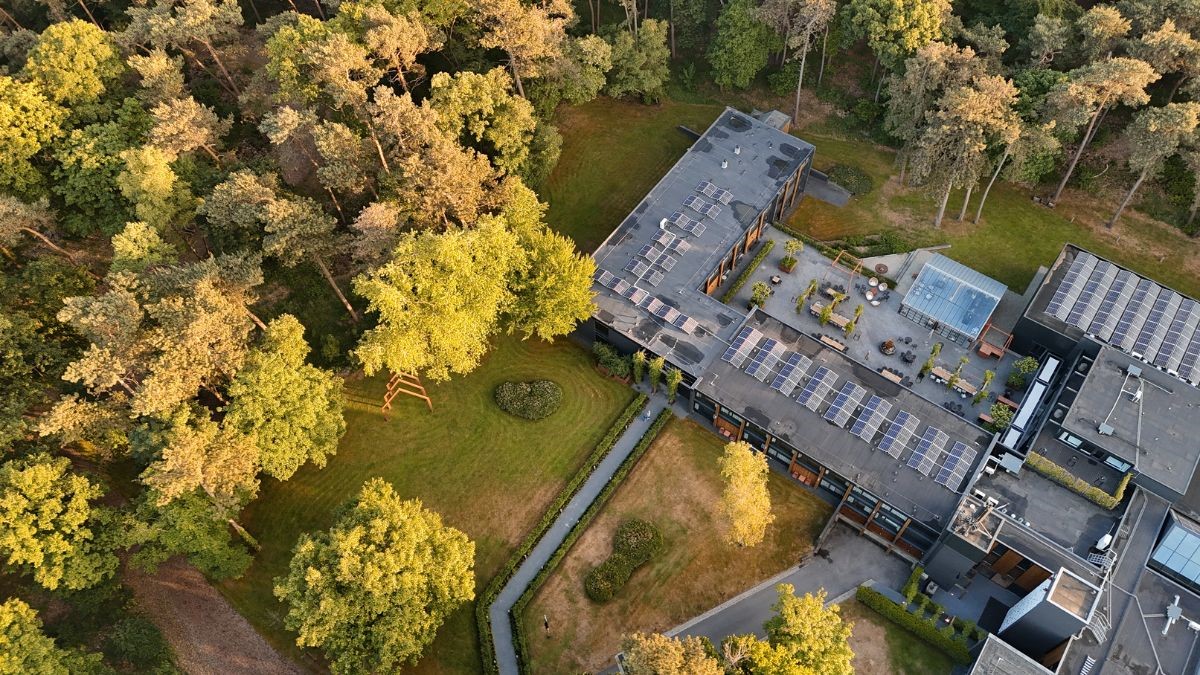 Luchtfoto van de Werelt Lunteren, duurzaam hotel en congreslocatie op de Veluwe met zonnepanelen en bosrijke omgeving